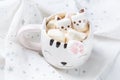 Mug with hot chocolate and melted marshmallows in the shape of cats, kittens