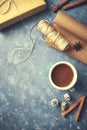 Mug of hot chocolate, spices, gift box and wrapping paper on gray background