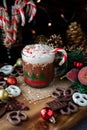 A mug of hot chocolate with whip cream, Christmas sprinkles and a candy cane.