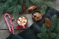 Mug hot coffee with milk, red candy cane on the wooden background with cone, branch of christmas tree and grey scarf. New Year. Ho Royalty Free Stock Photo