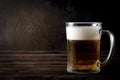Mug of light beer with foam on a dark wooden background, alcoholic beverage Royalty Free Stock Photo