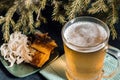 Mug of light beer with squid rings and pieces of fish on the background of fir branches Royalty Free Stock Photo