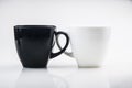 Mug mock up. Two ceramic mugs on white background. Blank coffee or tea mugs. Black cup and white cup. Copy space Royalty Free Stock Photo