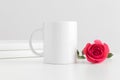 Mug mockup with books and a pink rose on a white table