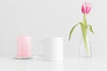 Mug mockup with pink tulips in a vase and candle on a white table Royalty Free Stock Photo