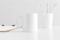 Mug mockup with workspace accessories on a white table