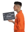 Mug shot of prisoner in orange jumpsuit with board on white background, side view