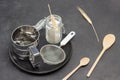 Mug for sifting flour and small sieve, glass jar with flour on black plate. Wheat spikelets and wooden spoon
