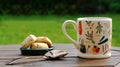 A mug of steamy green tea on a rustic wooden garden table in the back garden