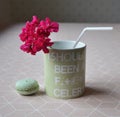 mug with straw and geraniums on the dining table