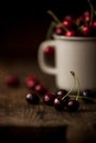 Mug with sweet red cherries on table