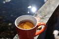 Mug With Tea And Autumn Leaves On The Railing Of The Bridge On The Background Of A Forest Lake, Close-up-the Concept Of A