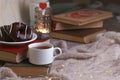 Mug with tea, books, donuts and woolen plaid winter blanket on vintage wooden table, autumn winter seasonal background, concept of