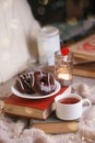 Mug with tea, books, donuts and woolen plaid winter blanket on vintage wooden table, top view, autumn winter seasonal background,