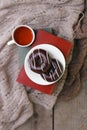 Mug with tea, books, donuts and woolen plaid winter blanket on vintage wooden table, top view, autumn winter seasonal background,