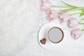 Mug of tea and pink tulips. Light wooden background. Royalty Free Stock Photo
