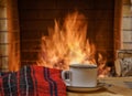 A mug of tea and woolen thing near a cozy fireplace, in a country house, winter or autumn holidays