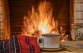 A mug of tea and woolen thing near a cozy fireplace, in a country house, winter or autumn holidays