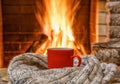 A mug of tea and woolen thing near a cozy fireplace, in a country house