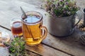 Mug of thyme tea, honey jar and rustic metal cup full of thymus serpyllum medicinal herbs