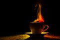 A mug with a warm drink and curly steam rising up, illuminated in red-yellow, orange on a black background