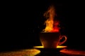 A mug with a warm drink and curly steam rising up, illuminated in red-yellow, orange on a black background