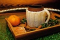 A mug of warm tea with pieces of manadarines on a wooden tray