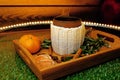 A mug of warm tea with pieces of manadarines on a wooden tray