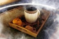 A mug of warm tea with pieces of manadarines on a wooden tray in the smoke