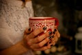 Mug with a warming drink in hands girls