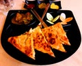 Mughlai paratha with potato curry salad and sauce in a black dish