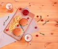 Mugs of beer, burgers, fried potatoes, rosemary and cherry tomatoes on wooden table