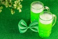 Mugs of green beer with leaves of shamrock on the green background. Celebration of St. Patrick`s Day. Famous irish festival