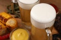 Mugs of tasty beer and snacks on table, closeup Royalty Free Stock Photo