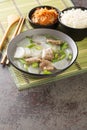 Muguk is an easy soup made with Korean radish and beef served with rice and kimchi closeup on the mat. Vertical