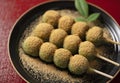 Mugwort dumplings covered with soybean flour, served on a black plate placed on a red tray