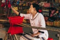 MUI NE, VIETNAM - MARCH 6, 2017: Female weaver works behind traditional Asian silk yarn weaving machine