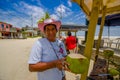 Muisne, Ecuador - March 16, 2016: Local street vendor posing happily with green coconut, beachside pacific ocean