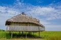 Muisne, Ecuador - March 16, 2016: Old traditional bungalow sitting on woden poles above grassy surface, beautiful blue