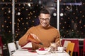 Mulatto boy sitting in the food spot and starting to eat using bottle with ketchup. Royalty Free Stock Photo