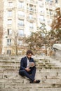 Mulatto businessman using tablet and sitting on steps. Royalty Free Stock Photo