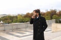 Mulatto laughing guy around Eiffel Tower with smartphone