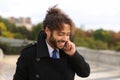 Mulatto laughing guy around Eiffel Tower with smartphone