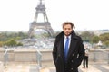 Mulatto laughing guy around Eiffel Tower with smartphone