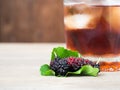 Mulberries with green leave on the the wooden table In front of the glass of Mulberry juice and ice. Mulberry this a fruit have a Royalty Free Stock Photo