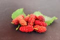 Mulberries with leaves on black background., organic Mulberry fruits with green leaves on selective focus