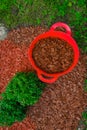 Mulching soil cover made of natural materials. chips for the garden.Red chips for mulching in red silicone bucket in a Royalty Free Stock Photo