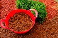 Mulching soil cover made of natural materials.Decorative chips garden. chips for mulching in red silicone bucket in a Royalty Free Stock Photo