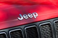 Closeup of logo on red jeep front parked in the street