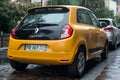Rear view of orange color Renault Twingo 3 parked in the street by rainy day